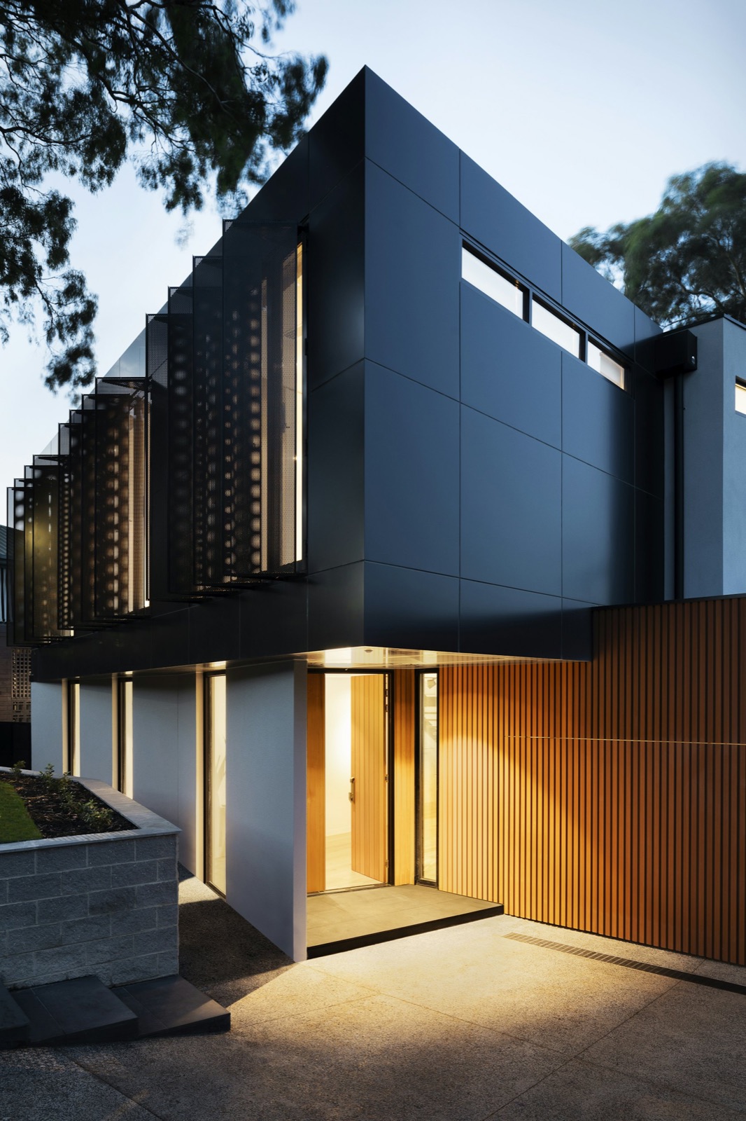 Dark-clad modern home with warm lighting at dusk